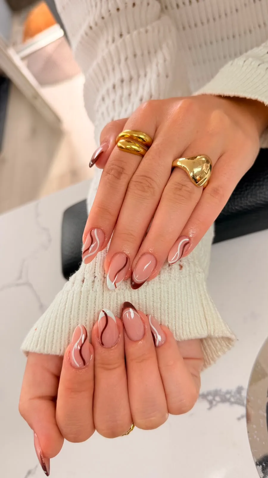 Nude mandelnegle med brune swirl-linjer